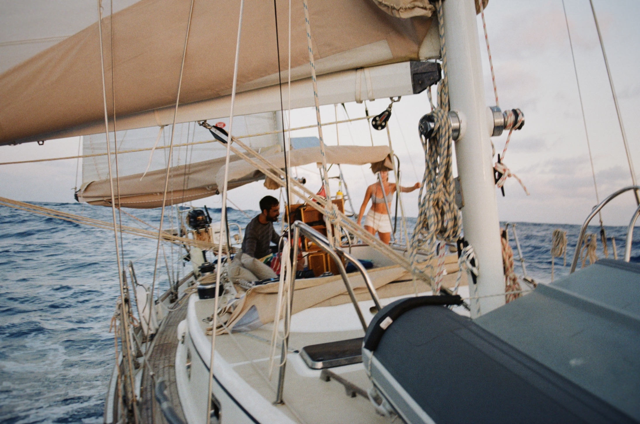 Two crew members working aboard a sailing yacht underway at sea